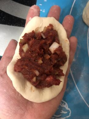 取一个小面团按扁，加入拌好的牛肉馅，可以多加一点。