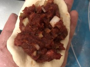 取一个小面团按扁，加入拌好的牛肉馅，可以多加一点。