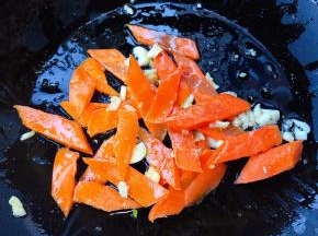 另起锅倒入底油加热放入蒜粒爆香再放入胡萝卜炒至变色