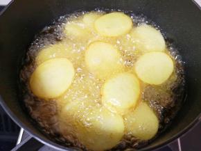 炸锅内倒多一些食用油烧热，下入土豆片炸至金黄色。