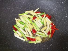 锅内留余油继续烧热，下入生姜、干红辣椒和小蒜蒜白部分炒香。