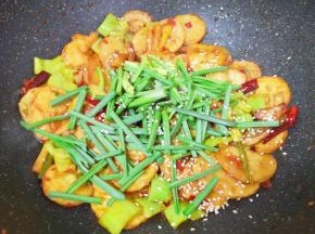 下入小蒜蒜叶部分和熟白芝麻，翻炒均匀关火出锅。