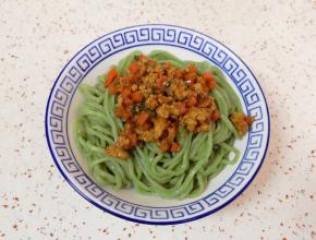 将面条盛在碗里，浇上胡萝卜肉酱。