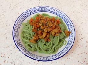将面条盛在碗里，浇上胡萝卜肉酱。