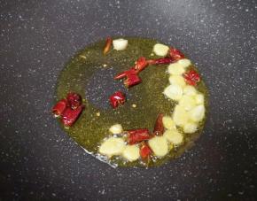 炒锅内倒适量的食用油烧热，下入蒜片和干红辣椒爆香。