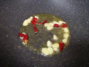 锅底留余油继续烧热，下入蒜片和干红辣椒炒香。