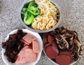 准备原材料毛肚、鸭血、木耳、油菜、豆皮、豆芽分别在开水中焯水去除杂质和断生后立即放入冷水中过凉沥干水分，午餐肉切片备用