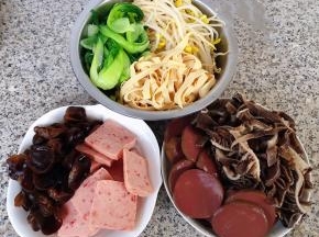 准备原材料毛肚、鸭血、木耳、油菜、豆皮、豆芽分别在开水中焯水去除杂质和断生后立即放入冷水中过凉沥干水分，午餐肉切片备用