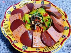 将入味的午餐肉、毛肚、鸭血、木耳摆放在蔬菜上面