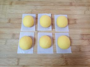 将分好的南瓜面团揉光滚圆，整成椭圆形，放在油纸上。