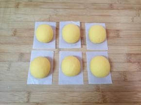 将分好的南瓜面团揉光滚圆，整成椭圆形，放在油纸上。