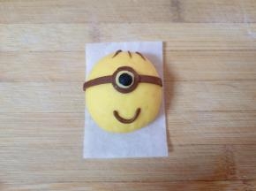 将可可面团擀成薄薄的片，用剪刀剪出小黄人的装饰部分，黑色面团搓出小黄人眼睛的眼珠，各部件沾水将小黄人组装好。