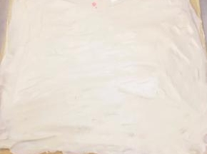 晾凉翻面，揭去油布，抹上淡奶油，放上橙子肉。用擀面杖卷住油纸，顺势往上推，卷起来，两边跟拧糖一样拧起来。放入冰箱冷藏半小时后再切块食用。