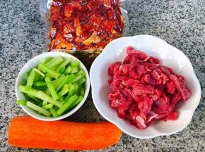 准备原材料芹菜摘好洗净切小段在开水中焯水断生后立即放人冷水中过凉再沥干水份，牛肉切成小条，胡萝卜去皮和香辣酥备用