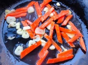 锅中倒入底油加热放入蒜片爆香再放入胡萝卜炒至变色