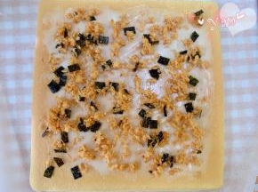 蛋糕卷的正面朝上，抹上沙拉酱，撒上海苔肉松。