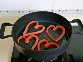 锅中刷上少许油，将火腿肠做出爱心形状，小火加热。