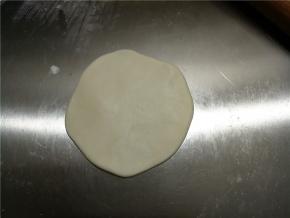 取一份小面团，擀成饺子皮状，中间厚边缘薄。