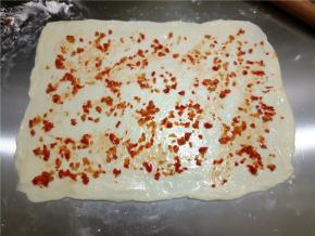 然后将剁椒尽量均匀抹平，剁椒不要带汁，水多了影响面团口感。可以不放剁椒，也可以换成其它酱。
