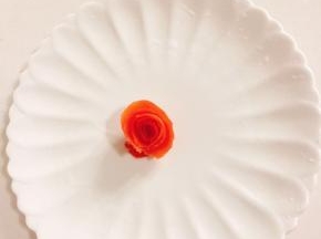 番茄皮卷成一朵花的形状，用牙签固定放在盘子中间！