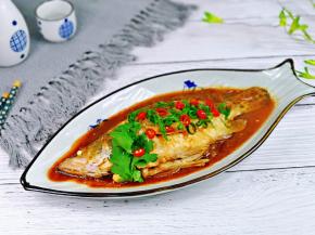 再把酱汁淋在鱼身上，撒上葱花，红辣椒段，香菜叶。