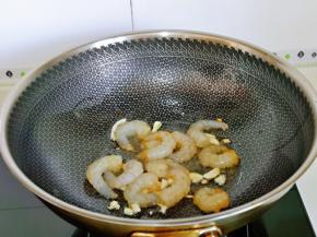 起油锅，加入切好的蒜炒香，再加入腌制好的虾仁煸炒。