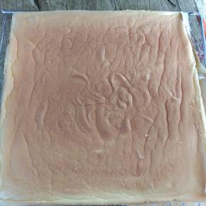 烤好的蛋糕卷取出凉凉，下面铺一层油纸，蛋糕卷倒扣，轻轻撕去底部油纸