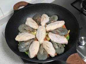 将腌渍好的鸡翅和虾码在蔬菜表面；