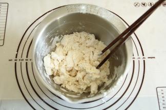 将水倒入面粉中，一边倒一边用筷子搅拌成絮状。水要慢慢加，不要一次性加入，面粉的吸水量略有差异。请根据状态看是否要全部加入水量。