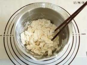 将水倒入面粉中，一边倒一边用筷子搅拌成絮状。水要慢慢加，不要一次性加入，面粉的吸水量略有差异。请根据状态看是否要全部加入水量。