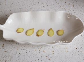 将姜片铺在蒸鱼盘的底部，可以预留两片，一些放在鱼肚子里，一些放面上，蒸鱼的时候，姜片不能少。