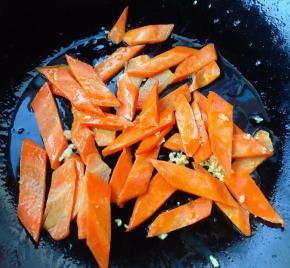 另起锅倒入少许底油加热放入蒜粒爆香再放入胡萝卜炒至断生