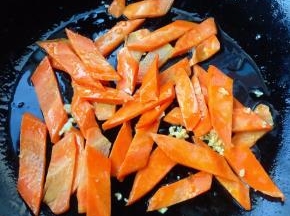 另起锅倒入少许底油加热放入蒜粒爆香再放入胡萝卜炒至断生