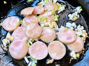 锅中倒入底油加热放入葱、蒜粒爆香再放入香肠翻炒片刻