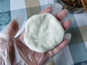 揪一团和乒乓球差不多大小的面团，稍微搓圆，然后用两个手掌按扁，弄成比饺子皮稍微小一点的面皮，将边缘捏薄一点。可能会有点粘手，可在手上抹一点油。其实就和包汤圆一样，可以不用面板，直接用手操作的。