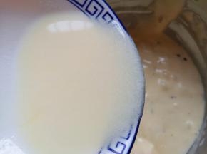 顺着盆边加入混合好的牛奶和玉米油，翻拌均匀，装进裱花袋。