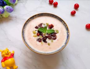 将做好的蔓越莓香蕉奶昔倒入小碗，放上南瓜籽和蔓越莓干。