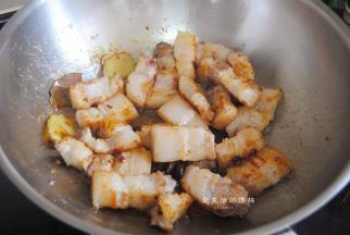 把刚煸出油的五花肉倒入锅里，转中大火翻炒均匀，看到猪肉开始变得紧实，倒入料酒翻炒出香气。