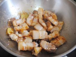 把刚煸出油的五花肉倒入锅里，转中大火翻炒均匀，看到猪肉开始变得紧实，倒入料酒翻炒出香气。