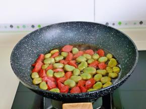 将香肠与蚕豆炒熟。