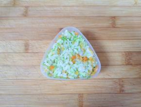 拌好的米饭放进饭团模具里面，盖上饭团模具的盖子压实（如果没有模具，直接用保鲜膜包起来捏成团也可以）。