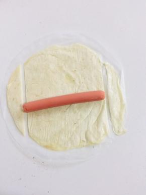 手抓饼稍微解冻，把火腿肠放在手抓饼上，切掉两边多余的部分！