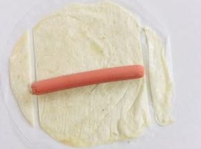 手抓饼稍微解冻，把火腿肠放在手抓饼上，切掉两边多余的部分！