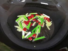 炒锅内倒适量的食用油烧热，下入葱白、姜丝和干红辣椒炒香。