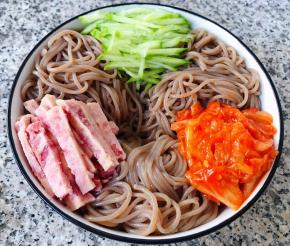 荞麦冷面和黄瓜、午餐肉、辣白菜依次摆入容器中