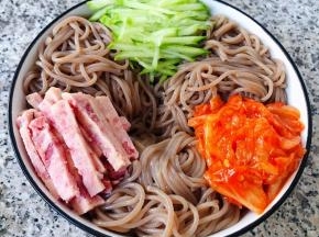 荞麦冷面和黄瓜、午餐肉、辣白菜依次摆入容器中