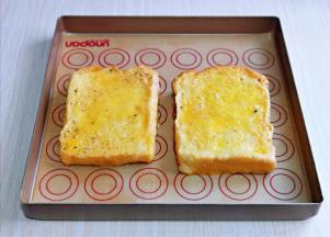 两片吐司均匀裹上蛋液，放入垫好油纸的烤盘中。