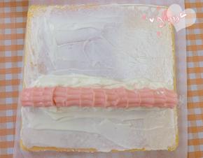 蛋糕卷的正面朝上，抹上淡奶油，放入花朵奶冻。