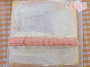 蛋糕卷的正面朝上，抹上淡奶油，放入花朵奶冻。