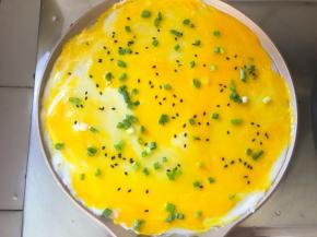 将鸡蛋抹均匀，撒上香葱和芝麻，煎至鸡蛋凝固